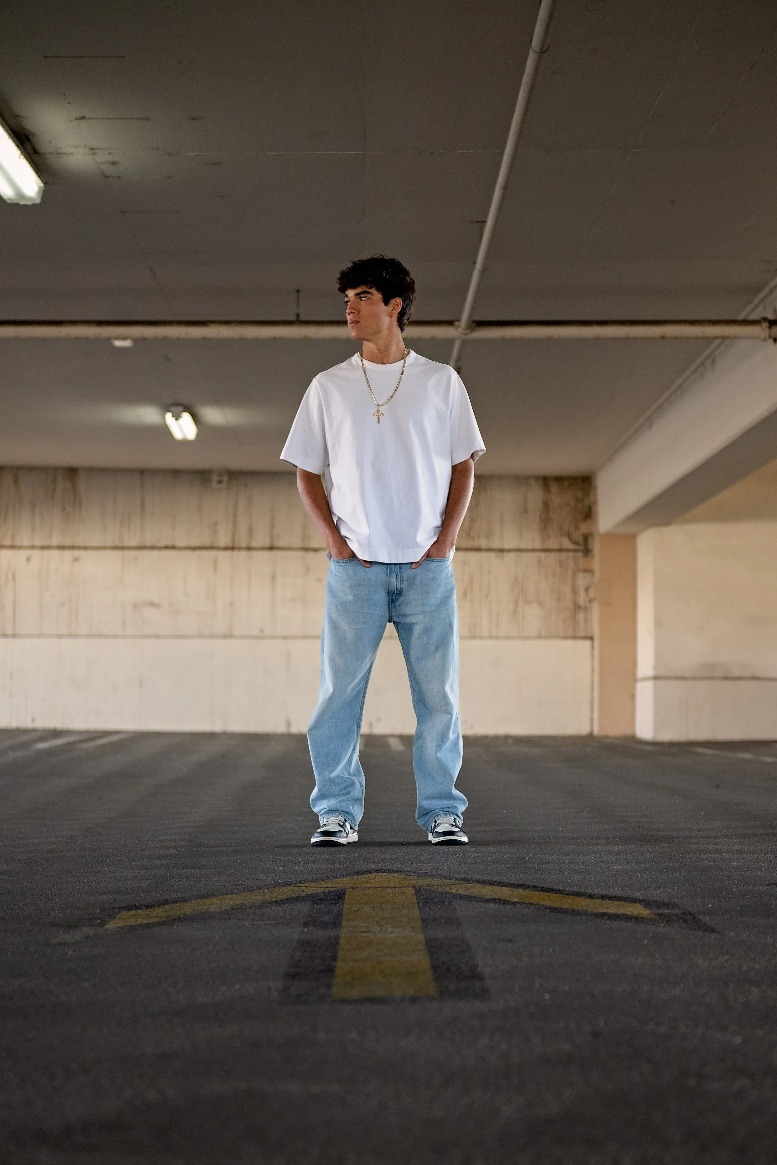 Salinas High School graduate Cruz standing in a parking garage during his urban senior portrait session in Salinas.