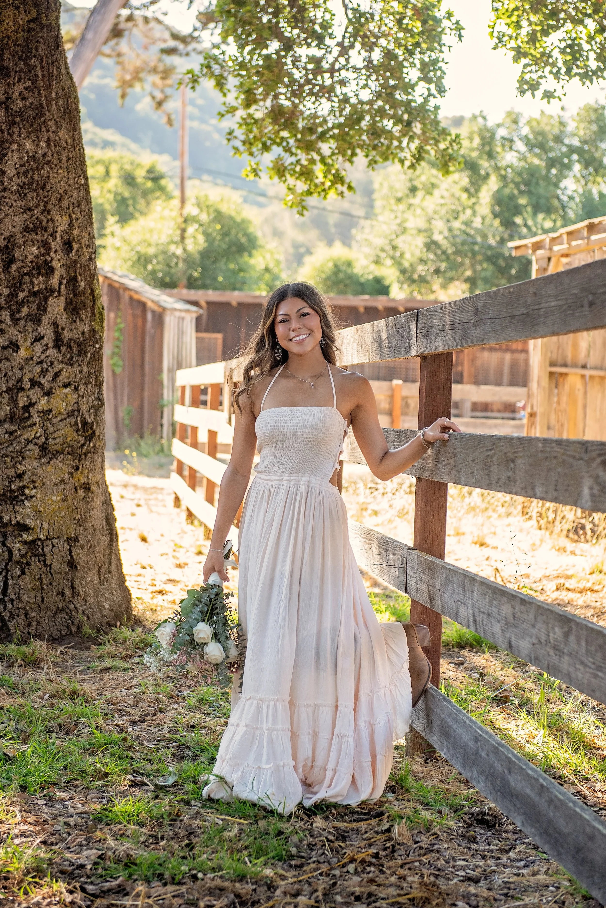 Salinas High senior Aubrey holding flowers beside a wooden fence at Garland Ranch in Carmel Valley