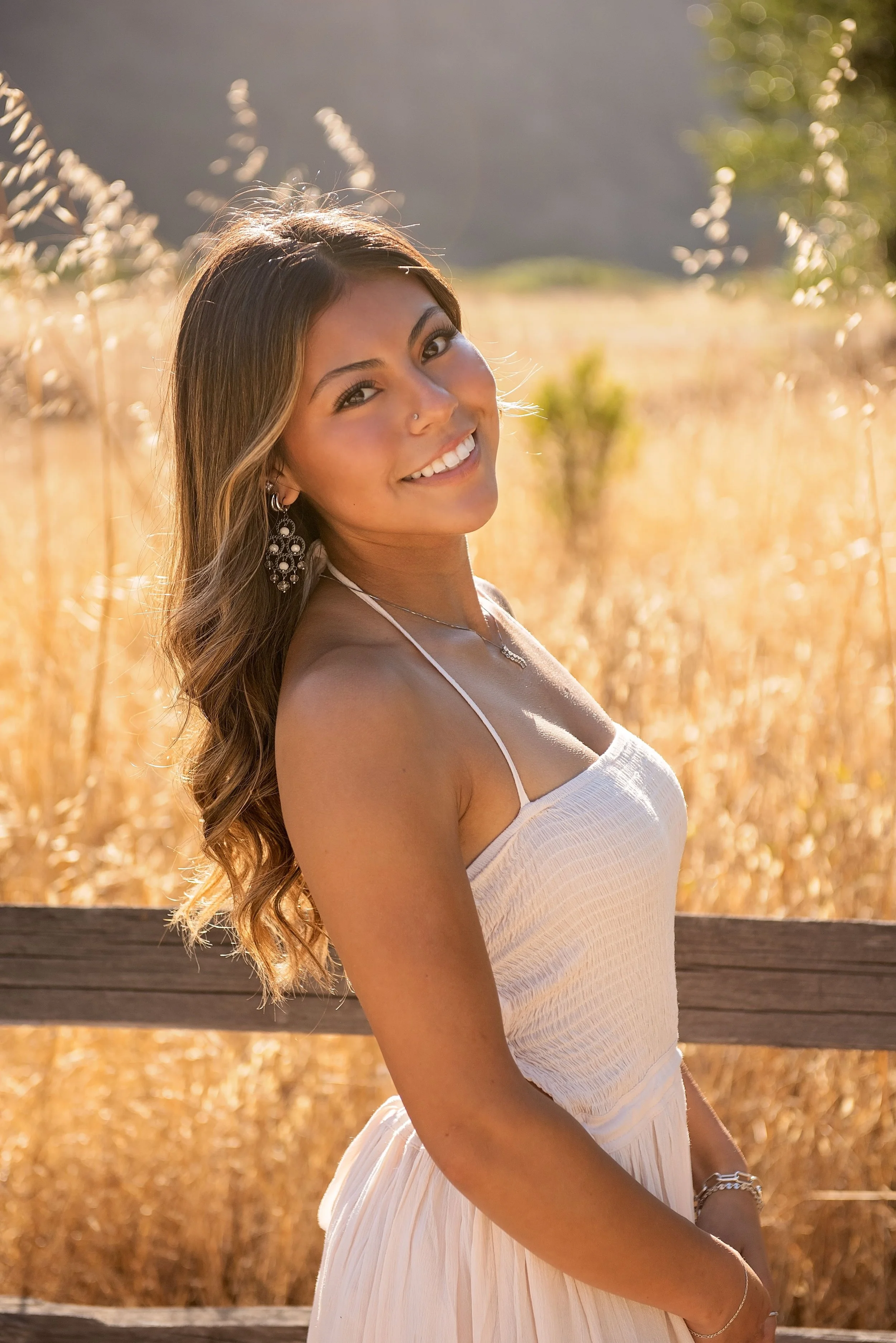 Golden hour senior portrait of Aubrey smiling in a white dress in the fields of Garland Ranch