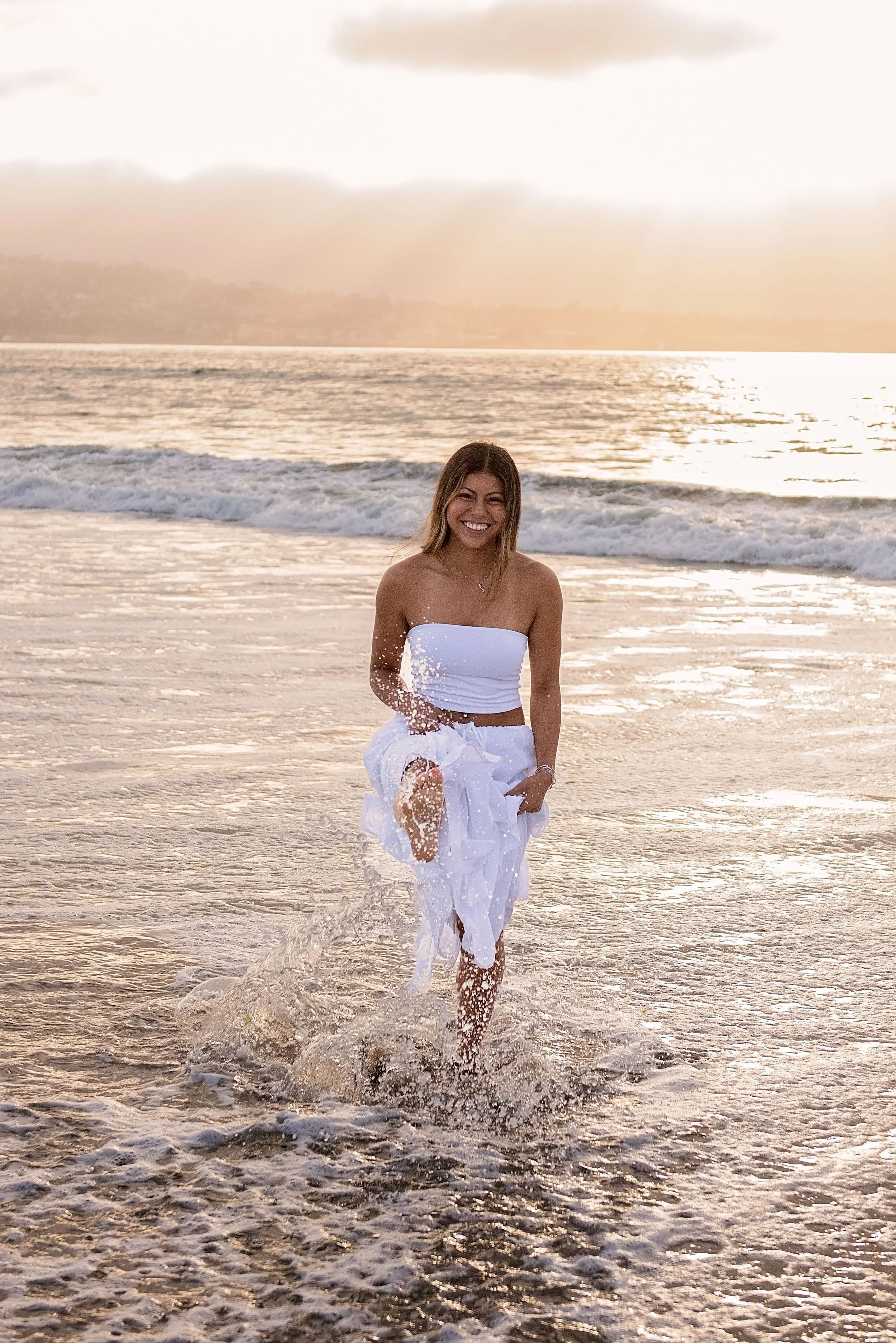 Aubrey running through the ocean waves at Del Monte Beach during her Monterey senior portrait session
