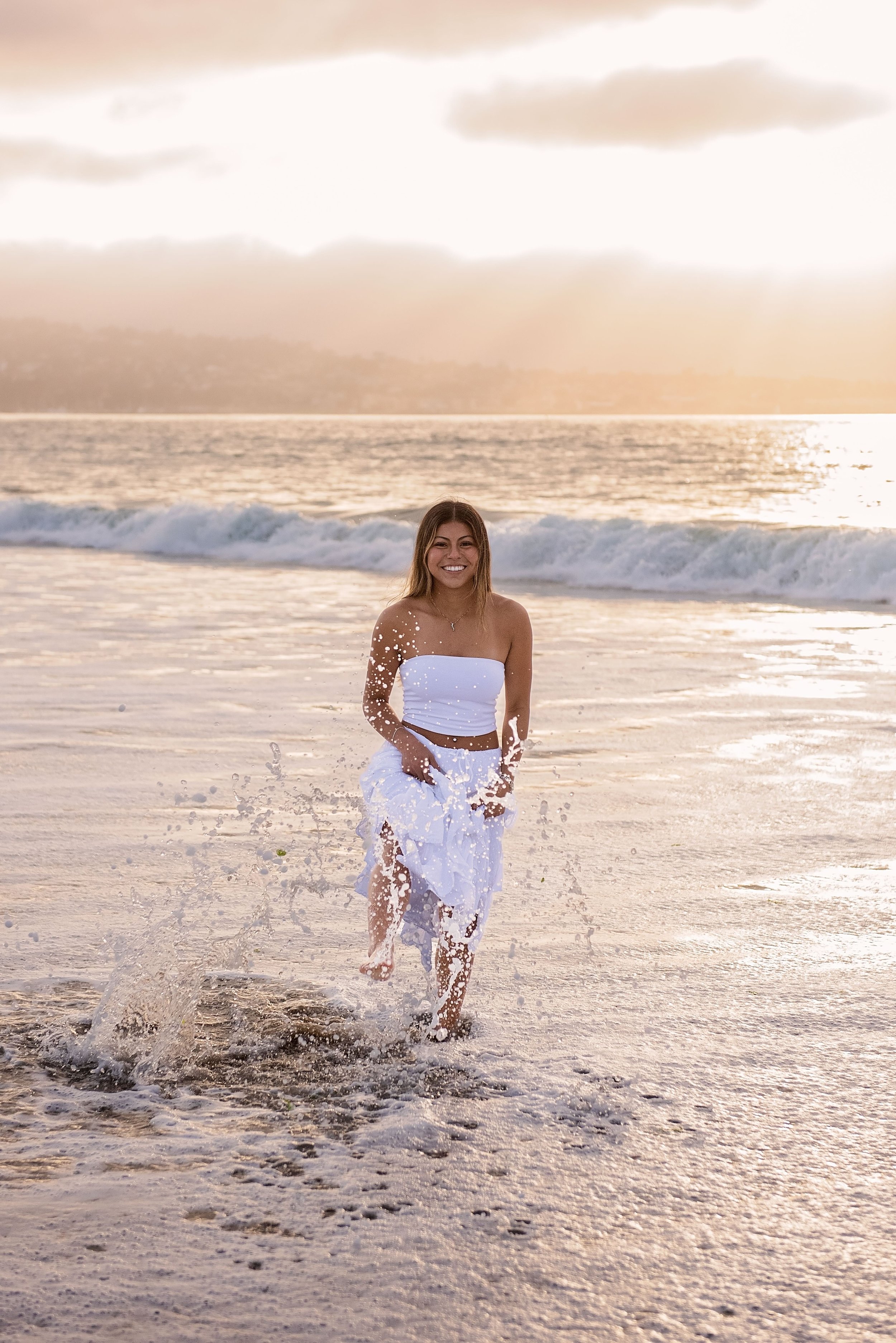 Salinas High senior Aubrey laughing and splashing through the waves during senior pictures at Del Monte Beach