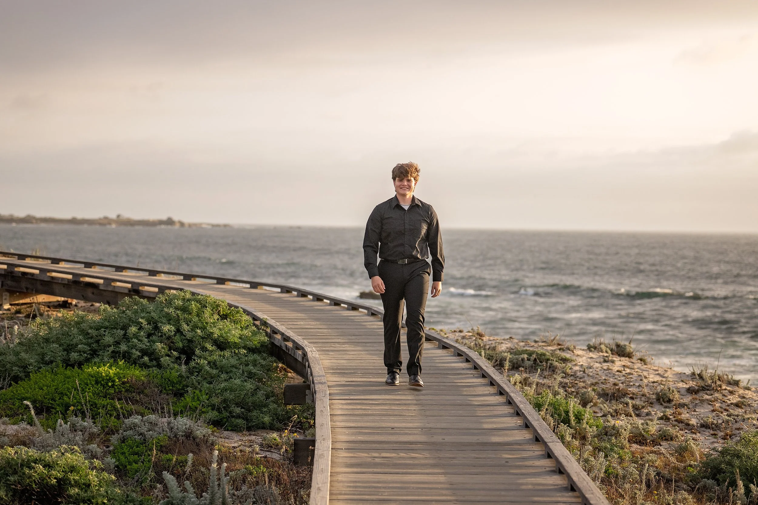 Gianni walking along the coastal boardwalk during his senior portrait session at Asilomar in Pacific Grove.