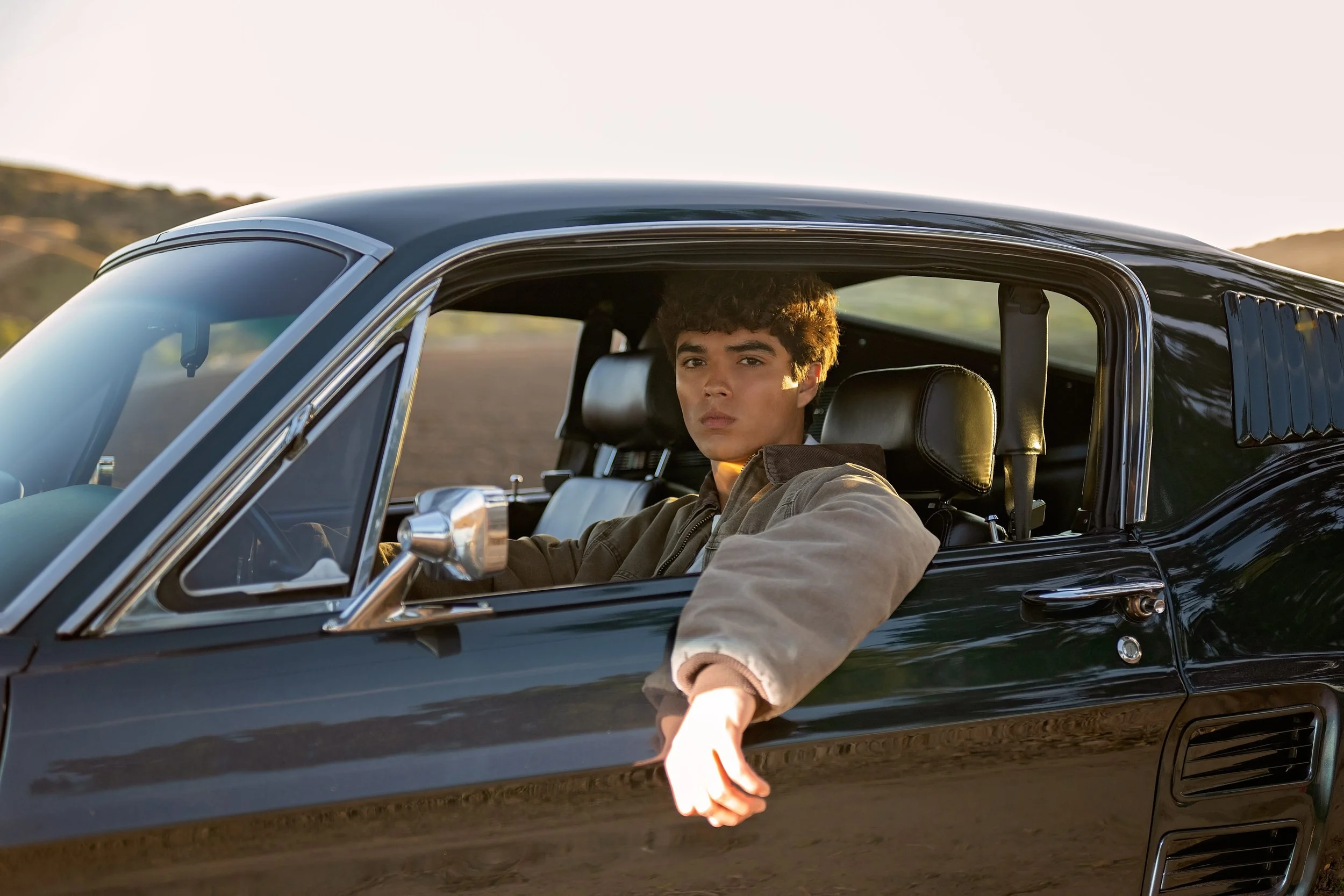 Senior portrait of Cruz sitting inside his vintage Mustang during golden hour in Spreckels, California.