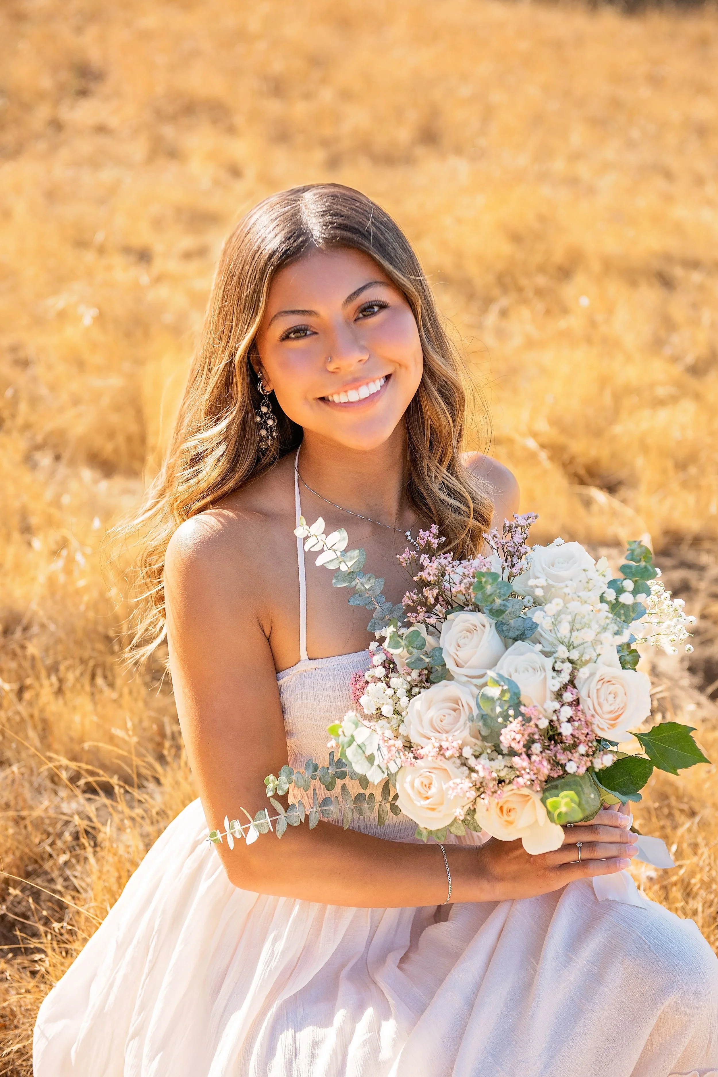 Close-up senior portrait of Aubrey holding a bouquet of flowers in a golden field at Garland Ranch