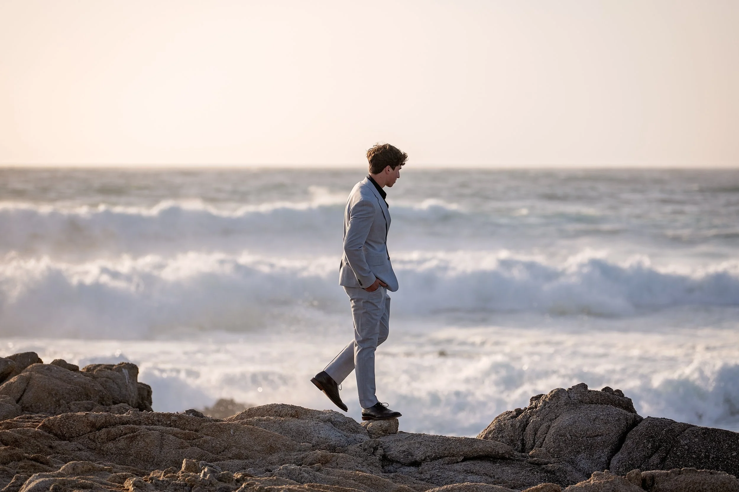 Grant walking along the top of the cliff looking out onto the ocean in Monterey