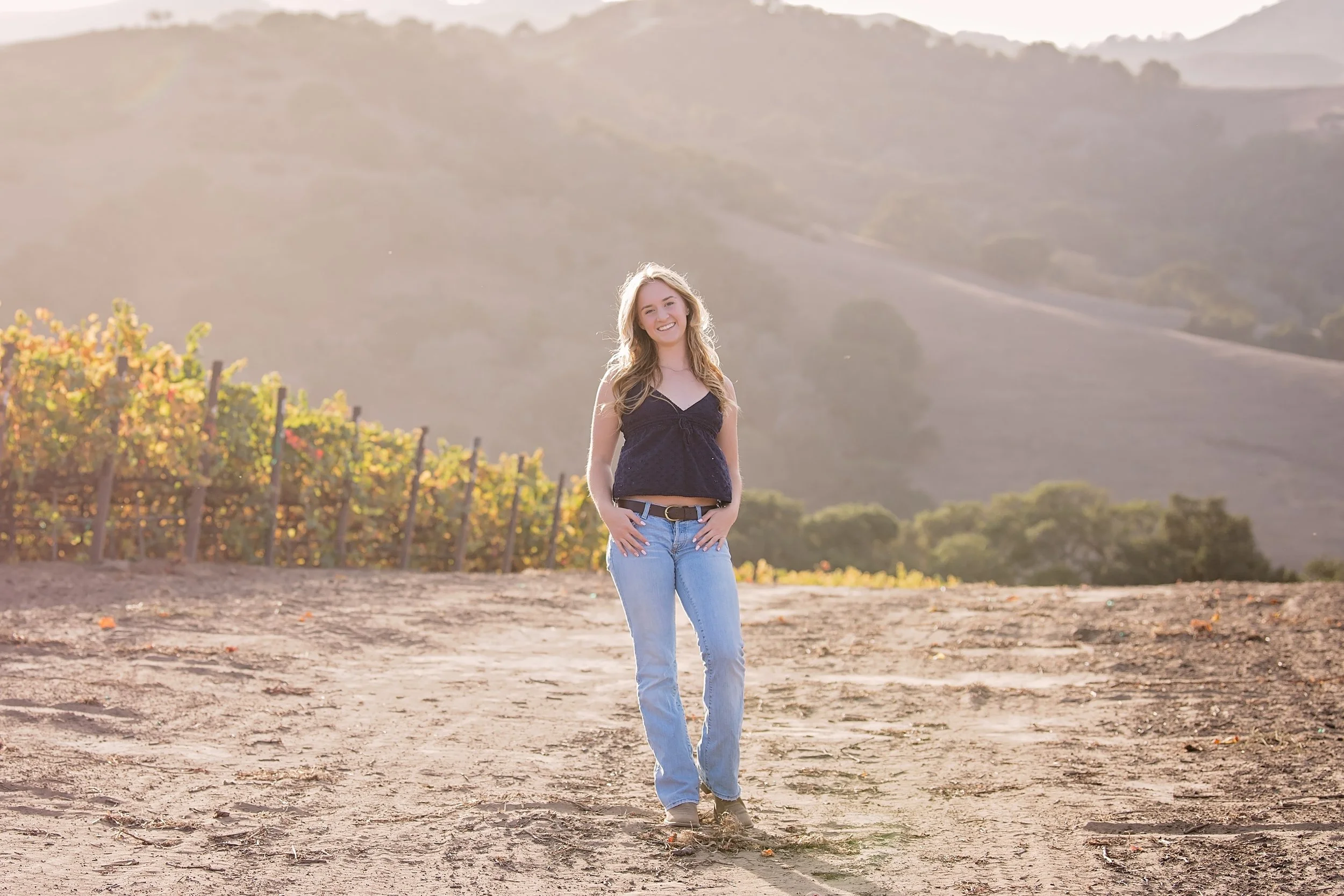Masion posing among vineyard rows during a senior portrait session in Salinas