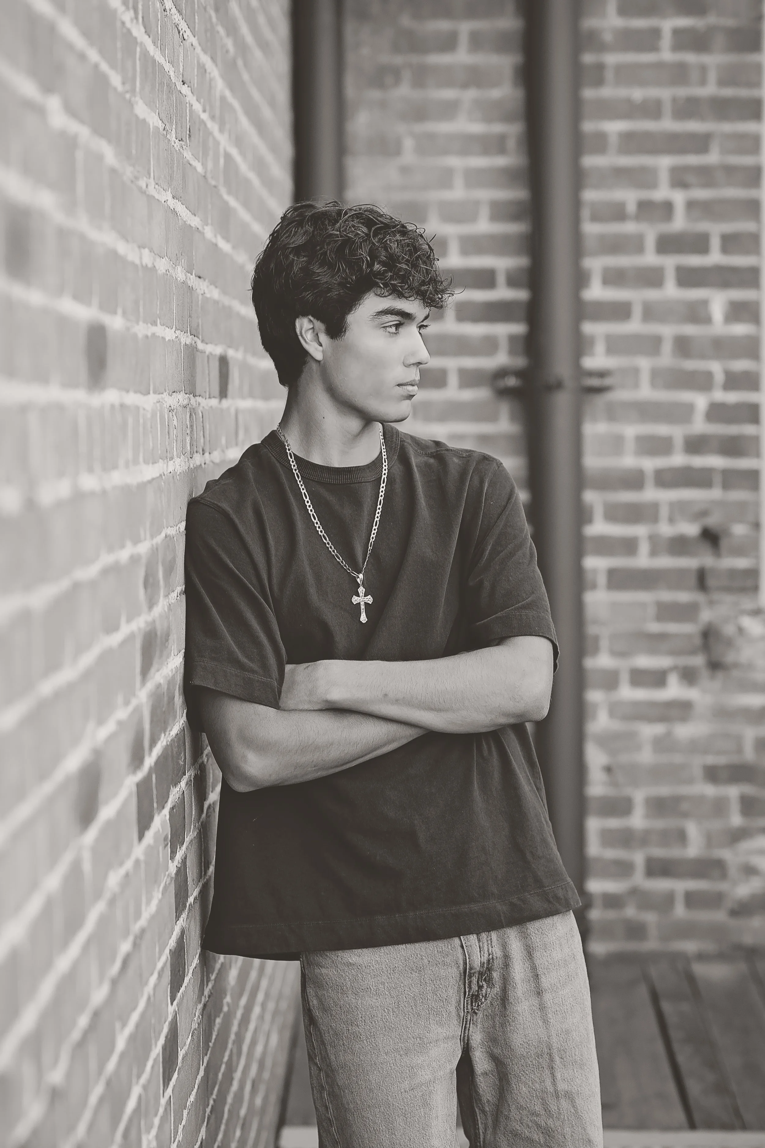 Black-and-white portrait of Salinas High School senior Cruz leaning against a historic brick wall in Downtown Salinas.