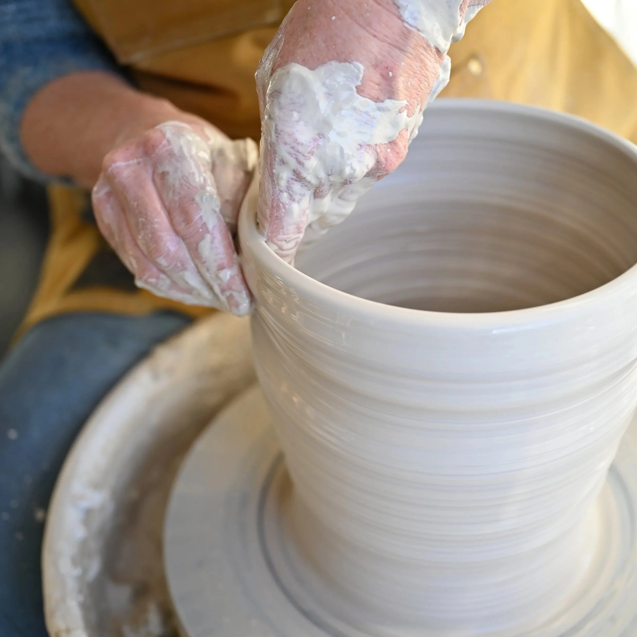 Hands centring clay on the wheel — What the Clay Teaches ceramics instruction at Il Baciarino, Tuscany