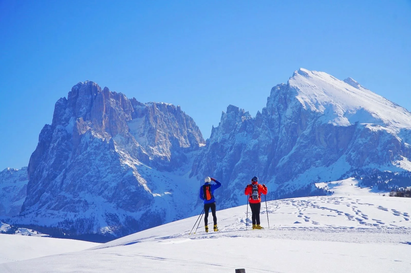 Cross-country skiers gliding along groomed trails on the snowy Seiser Alm, Italy.