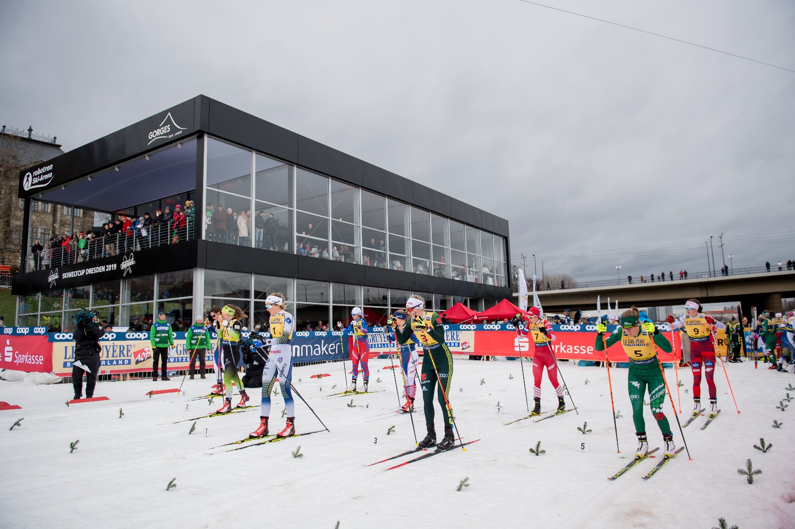 Racers line up for the Team Sprint in front of the VIP hospitality building
