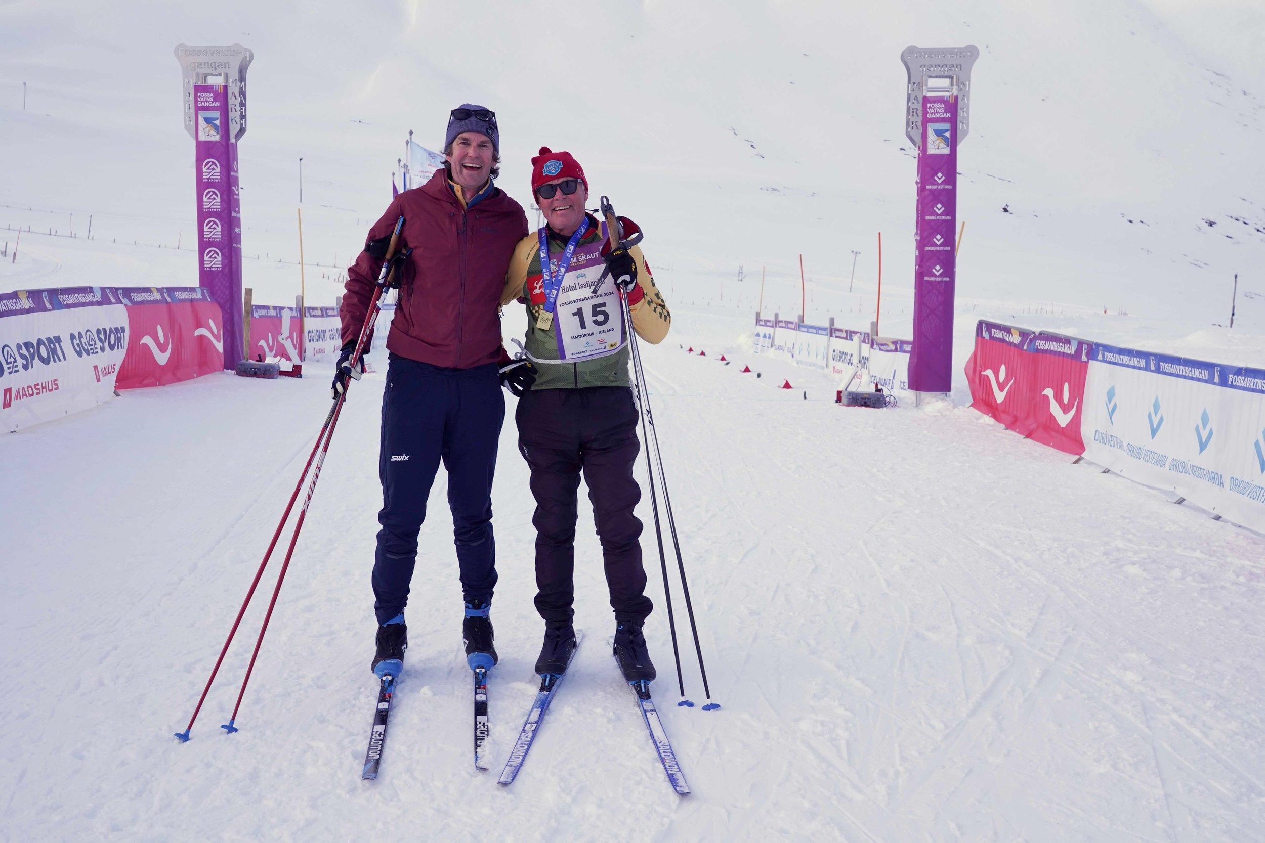 Garrott Kuzzy and Jim Kuzzy crossing the finish line of the Fossavatn 25 km sunset skate race in Iceland