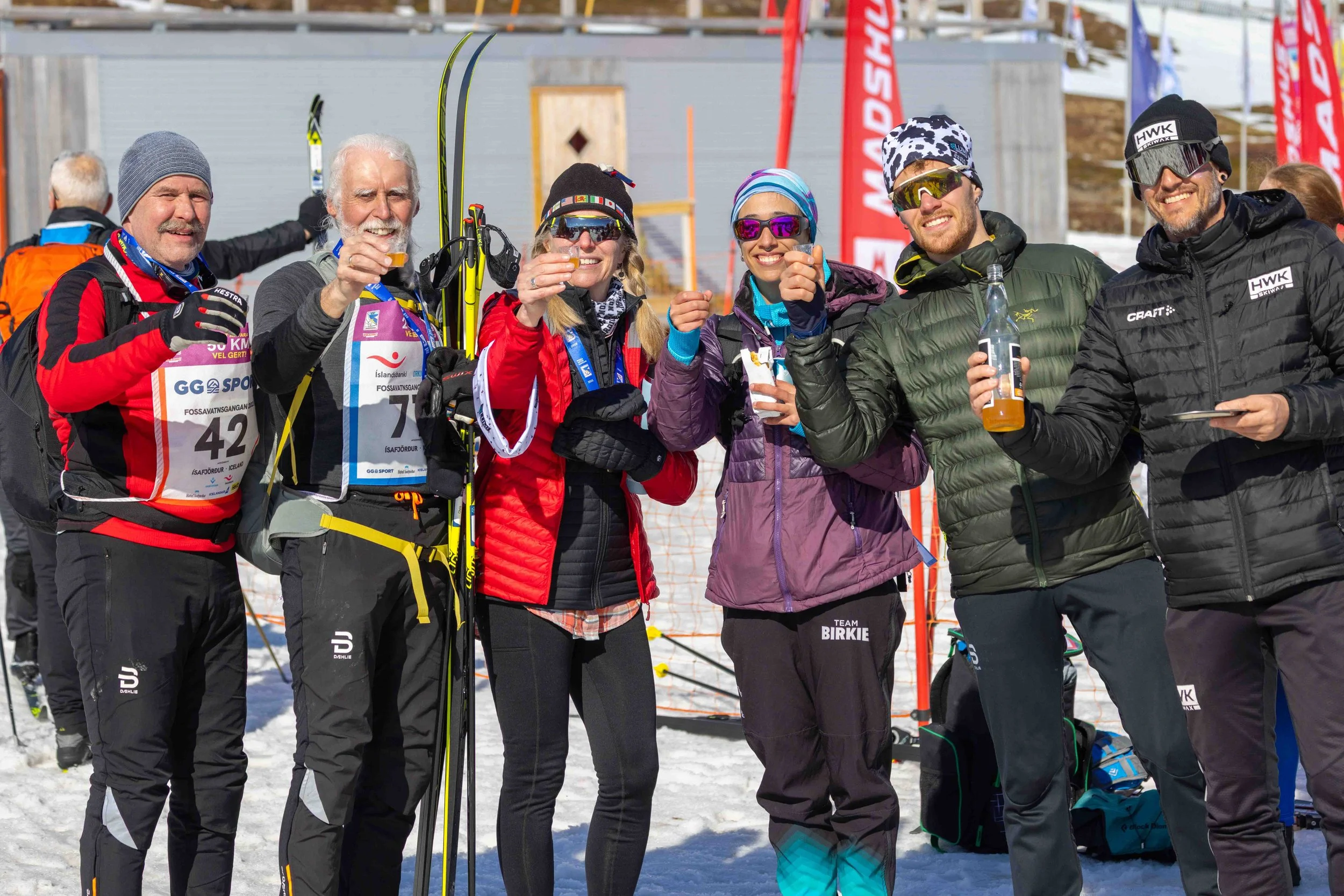Cross-country skiers raising a glass together in celebration after completing the Fossavatn Ski Marathon in Iceland