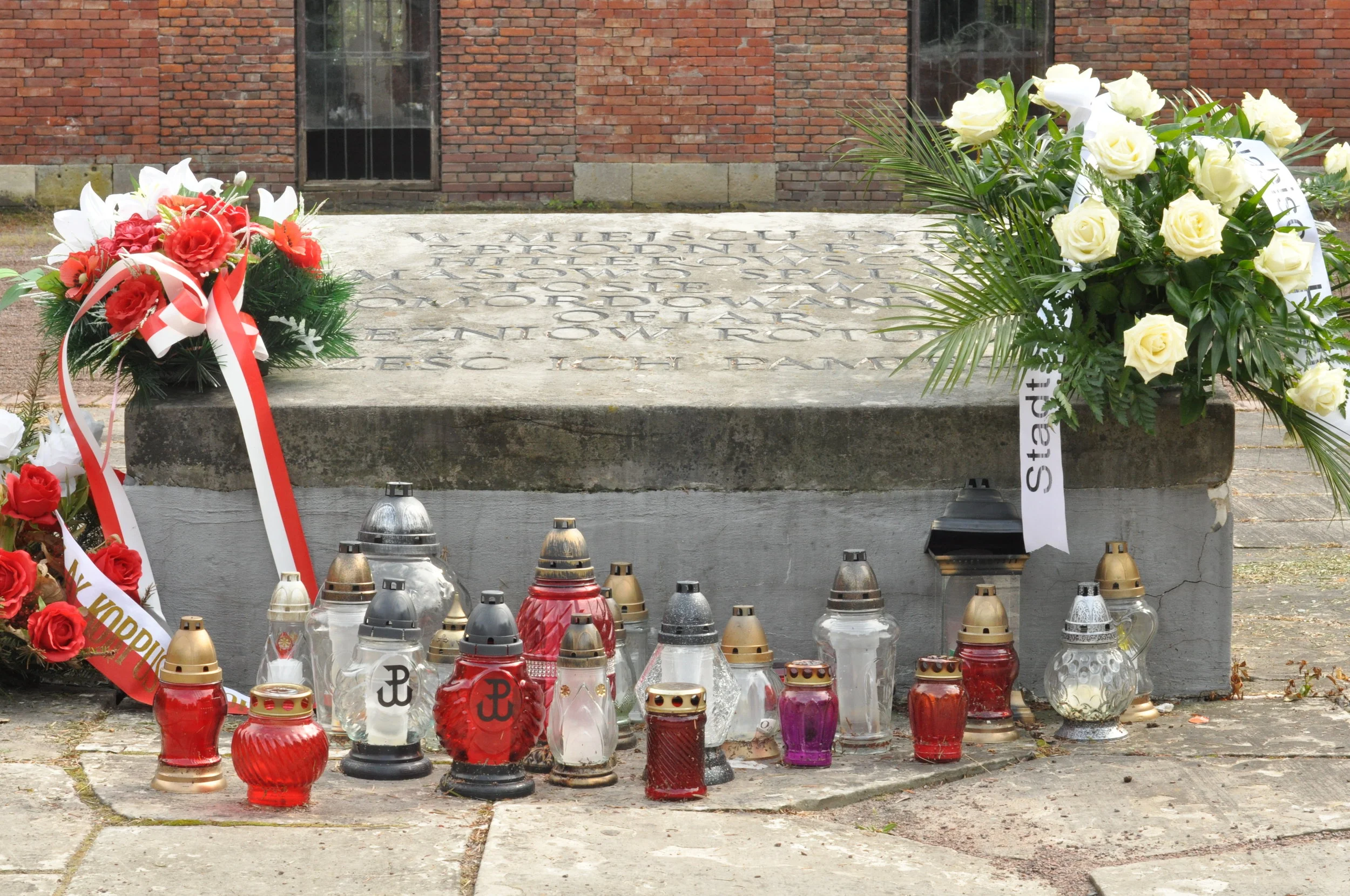 Flowers and candles surround the plaque commemorating those whose bodies were burned in the Rotunda in Zamosc, Poland during World War II. 