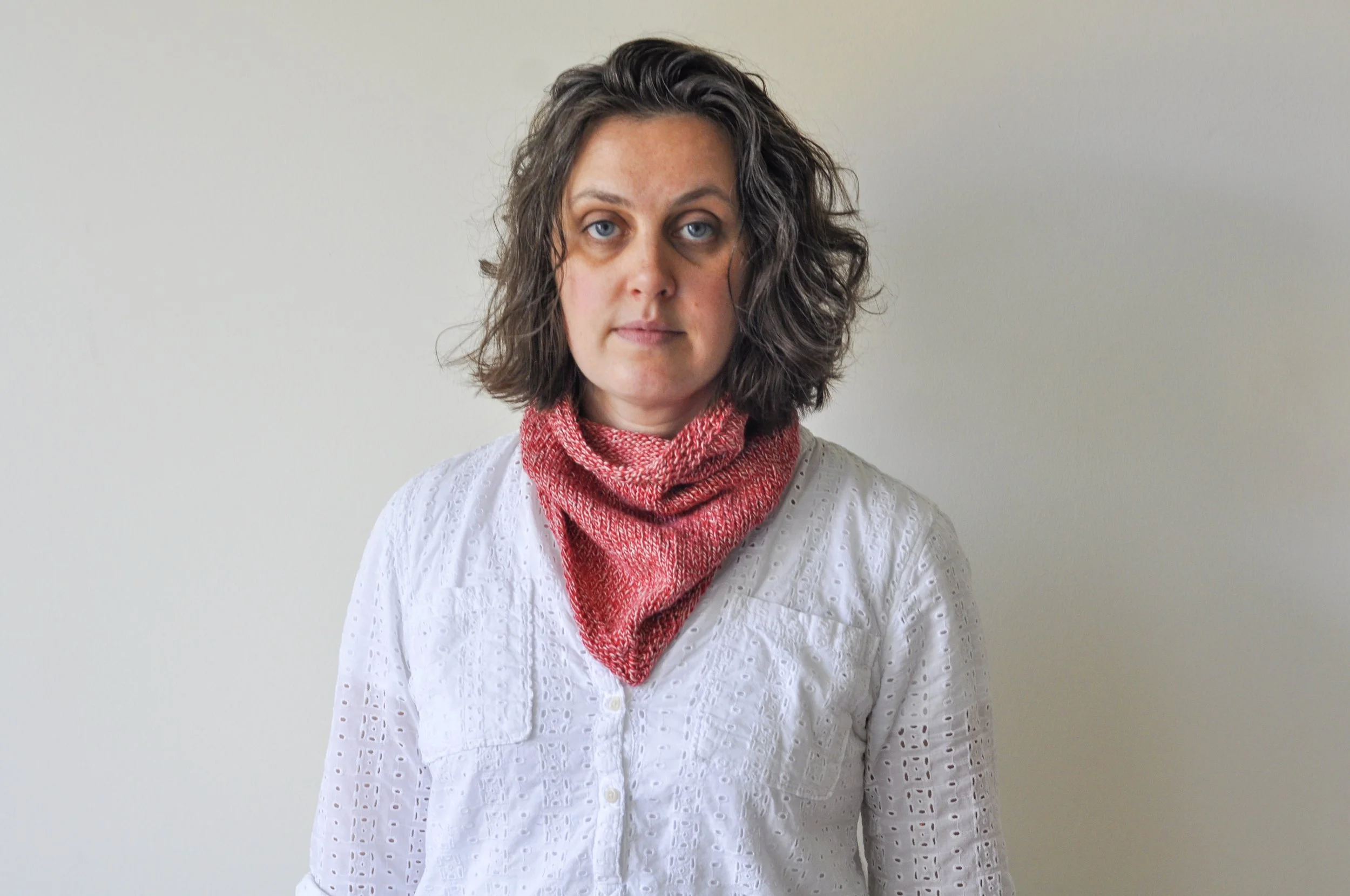 A woman wearing a Purl Soho Bandana Cowl in red variegated yarn