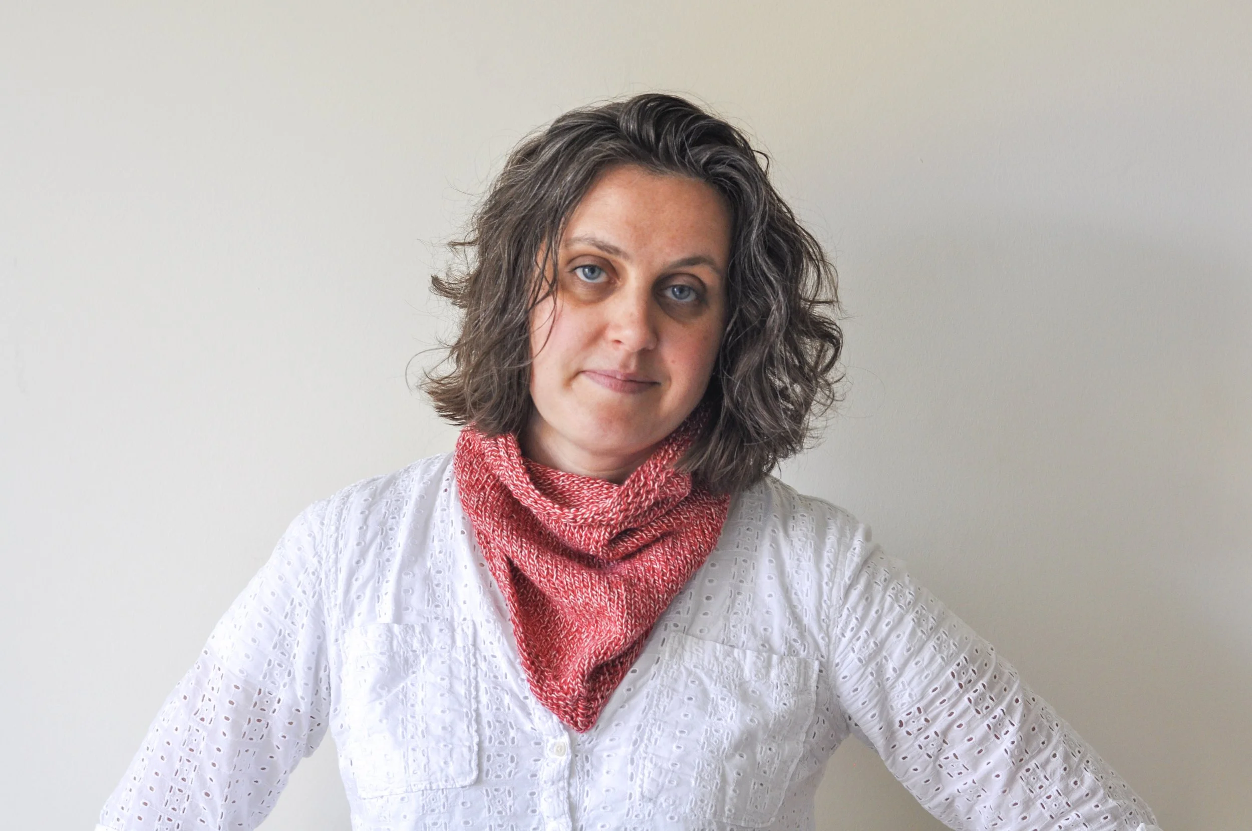 A woman wearing a Purl Soho Bandana Cowl in red variegated yarn