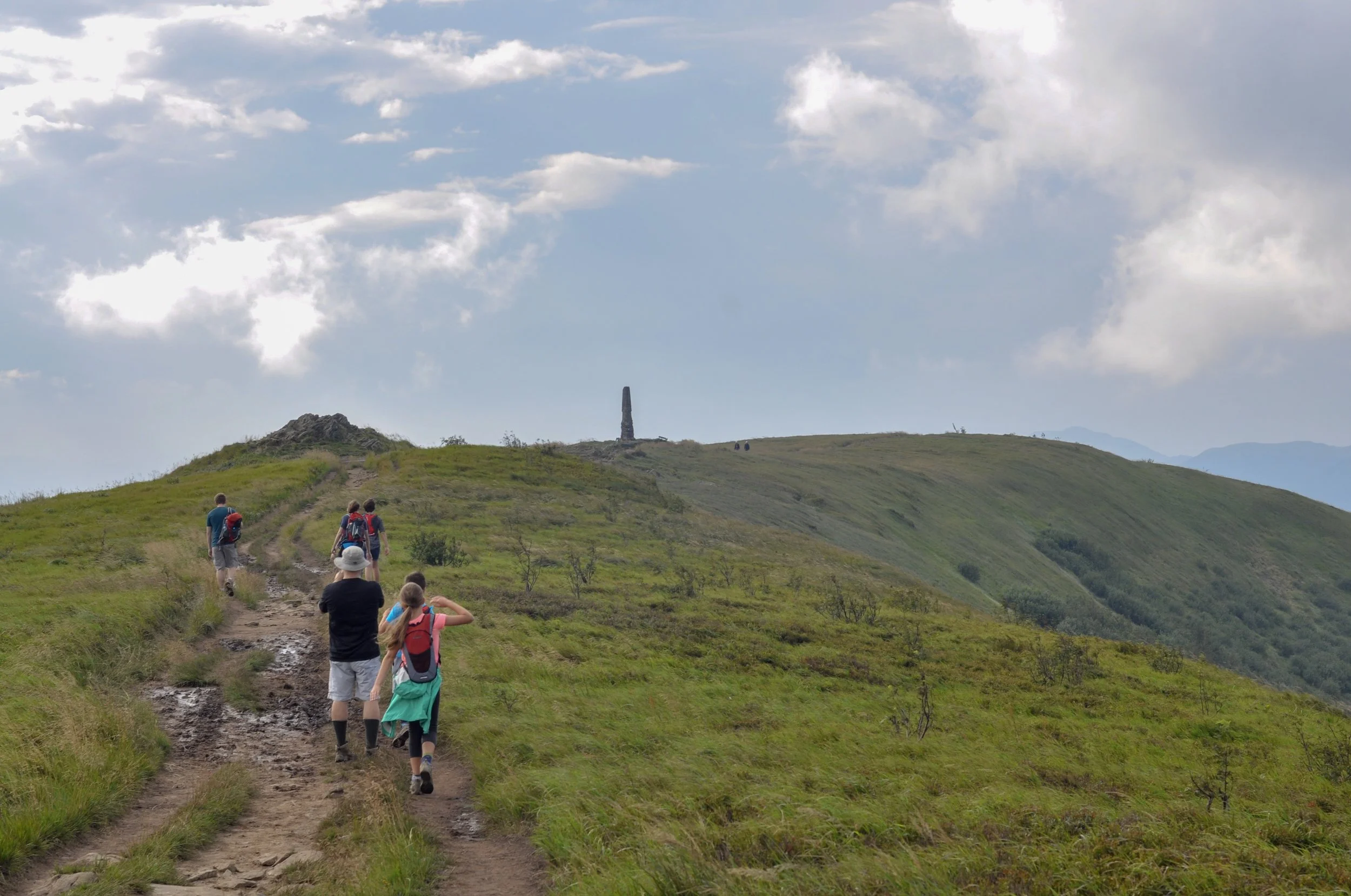 Hikers approaching the monument at Wielka Rawka on the Tri-Border hike in the Bieszcady Mountains