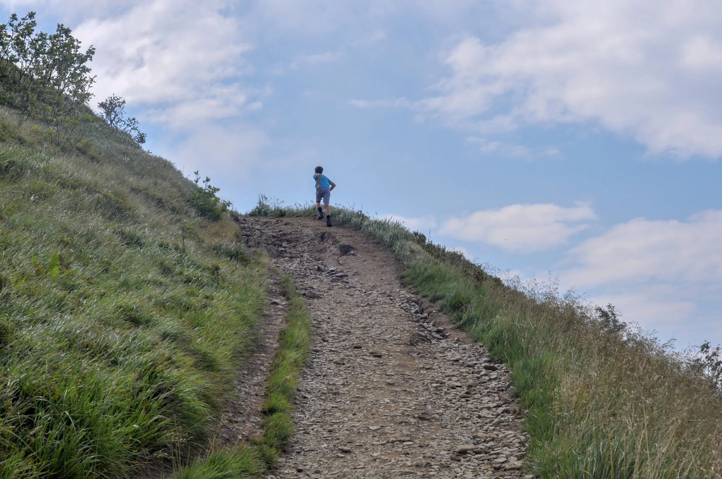 A boy runs up a hill on the trail to the Tri-Border area in the Bieszczady Mountains