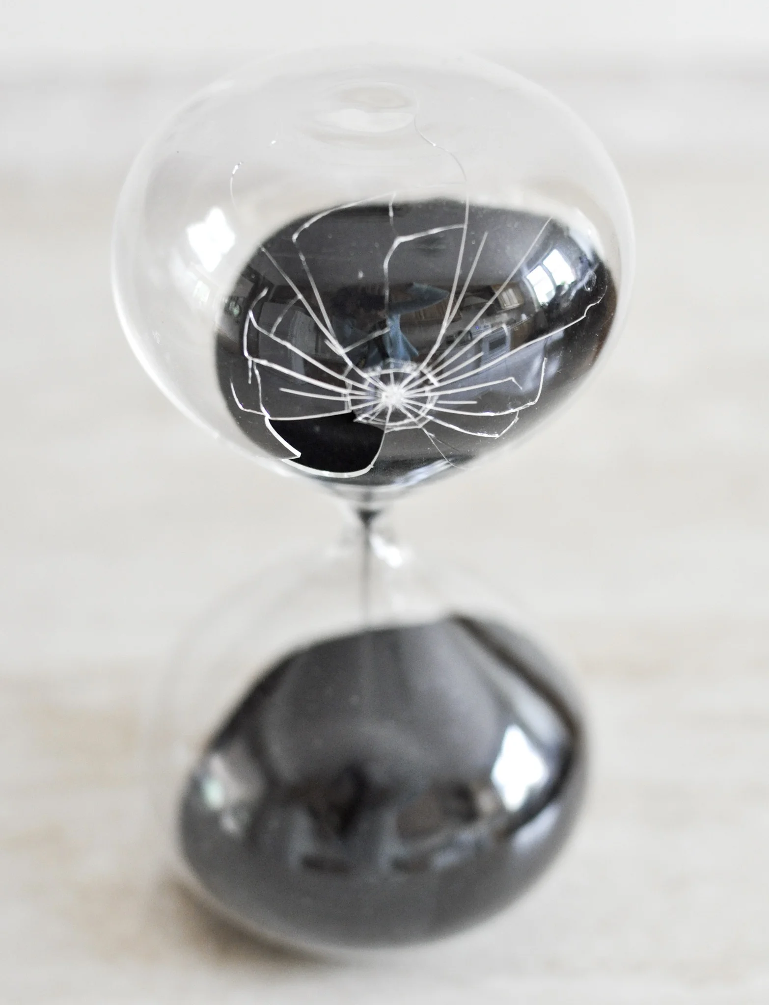 Glass sand timer with black sand and a shattered bulb