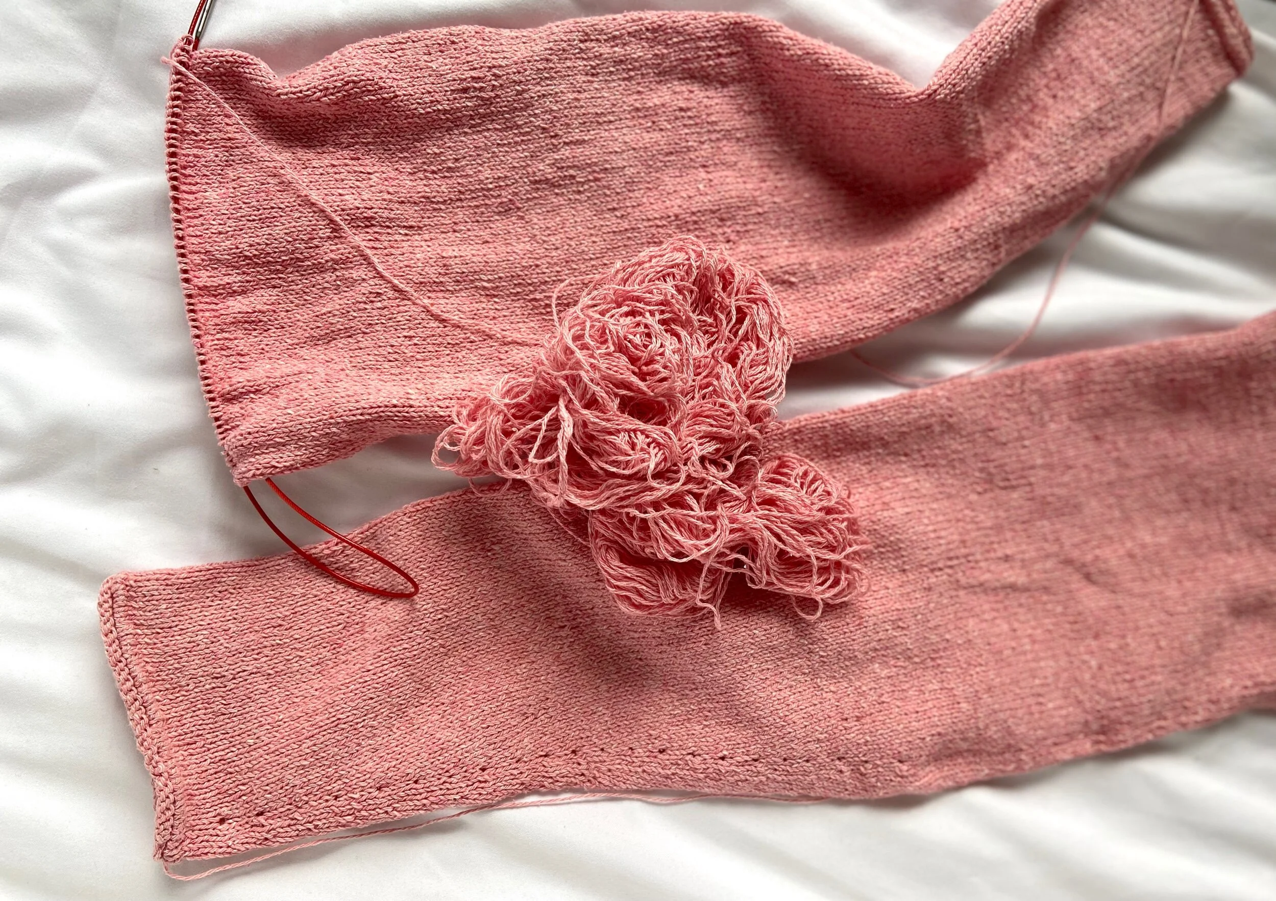 Pink sweater sleeves in the process of being knit