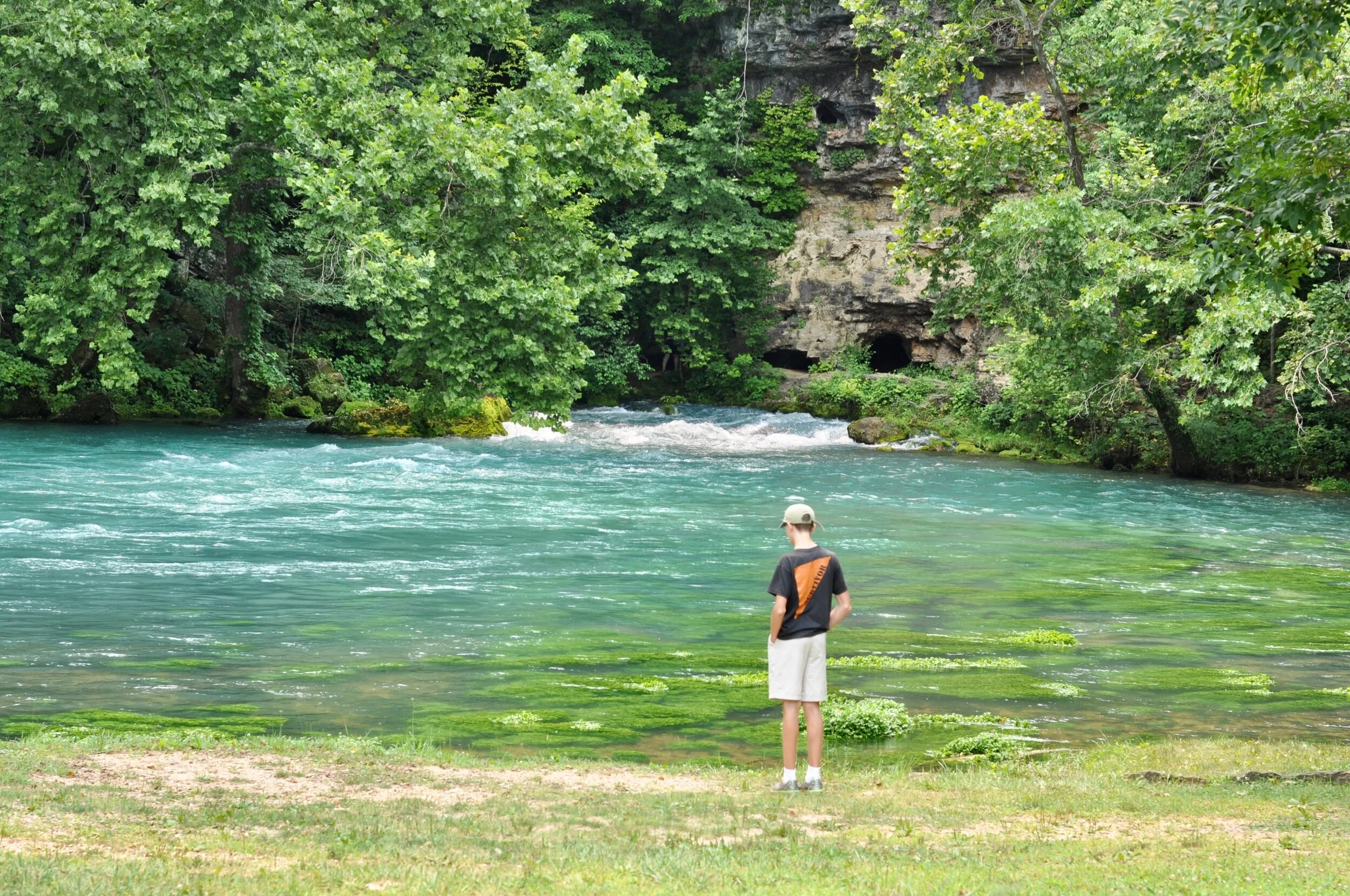 A person looking at the limestone rich water emerging from Big Spring, Missouri