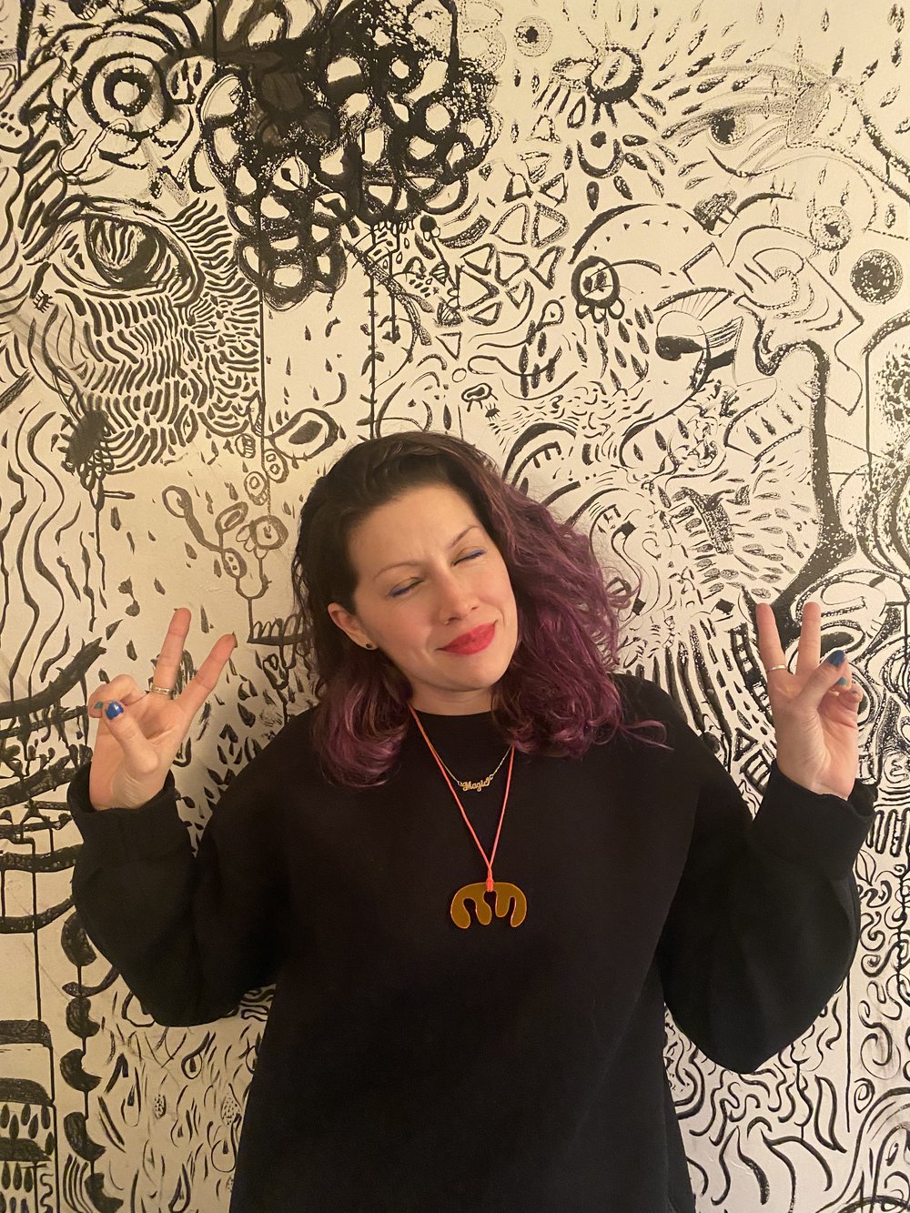 Maya in front of a doodle wall in her home