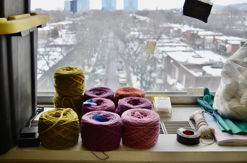 Cakes of yarn against a view of Montreal 