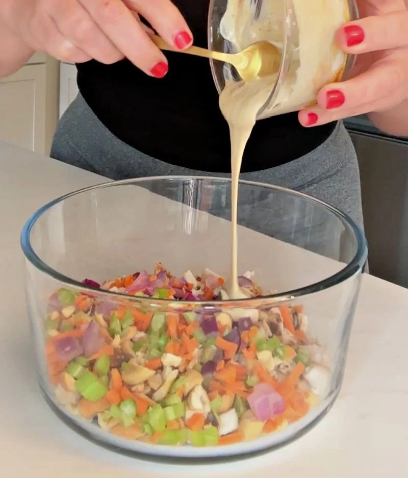 Honey mustard chicken salad with cashews, carrots, celery, and red onion in a glass bowl with avocado oil mayo dressing