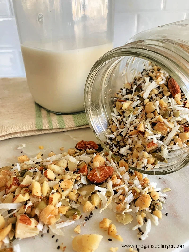 Homemade low carb breakfast cereal with chopped almonds, walnuts, macadamia nuts, pumpkin seeds, coconut flakes, and chia seeds in a bowl with almond milk and blueberries
