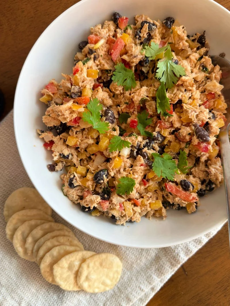 Southwest chipotle chicken salad in a bowl with red and yellow bell peppers, black beans, tomato, red onion, and cilantro