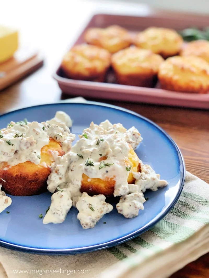 Golden almond flour cheddar biscuits fresh from a muffin tin, soft and buttery with visible cheddar throughout