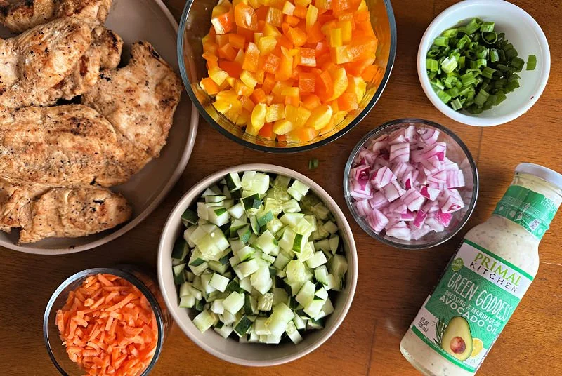 Grilled green goddess chopped chicken salad with cucumber, bell pepper, green onion, red onion, and carrots tossed in Primal Kitchen green goddess dressing