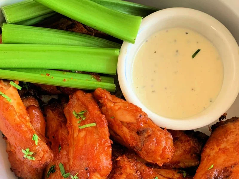 Crispy air fryer buffalo wings on a plate with high protein ranch dipping sauce and celery sticks