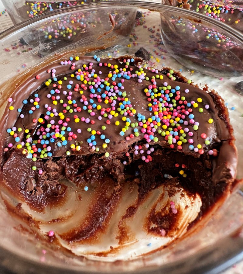 Cosmic brownie protein dessert cups in glass bowls with Lily's chocolate frosting and dye-free rainbow sprinkles on top