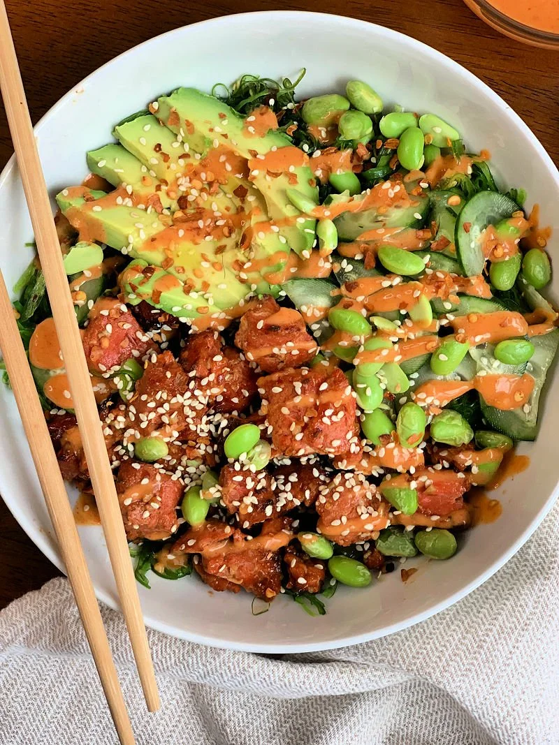 Honey sriracha salmon bowl with air fryer salmon bites, seaweed salad, edamame, cucumber, and spicy sriracha mayo drizzle