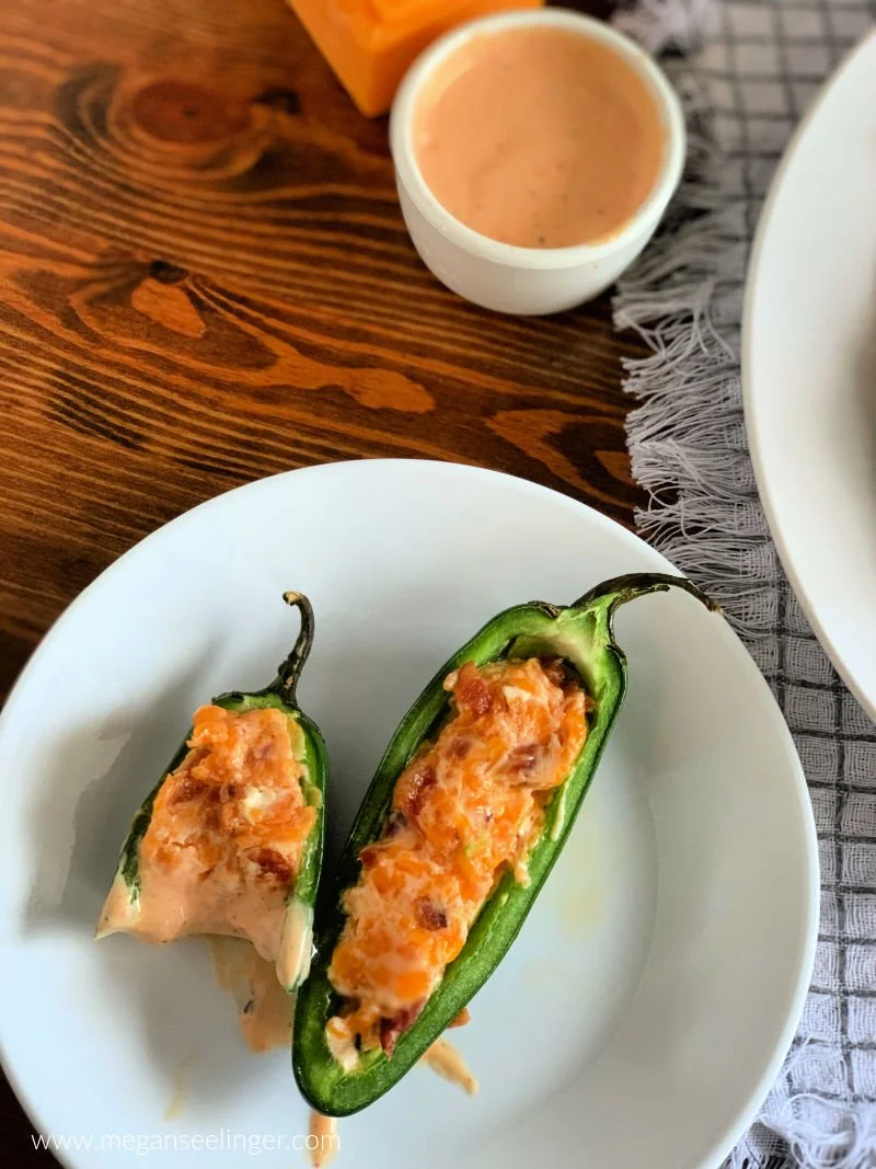 Easy jalapeño poppers with cream cheese cheddar filling and crispy bacon on a white serving plate