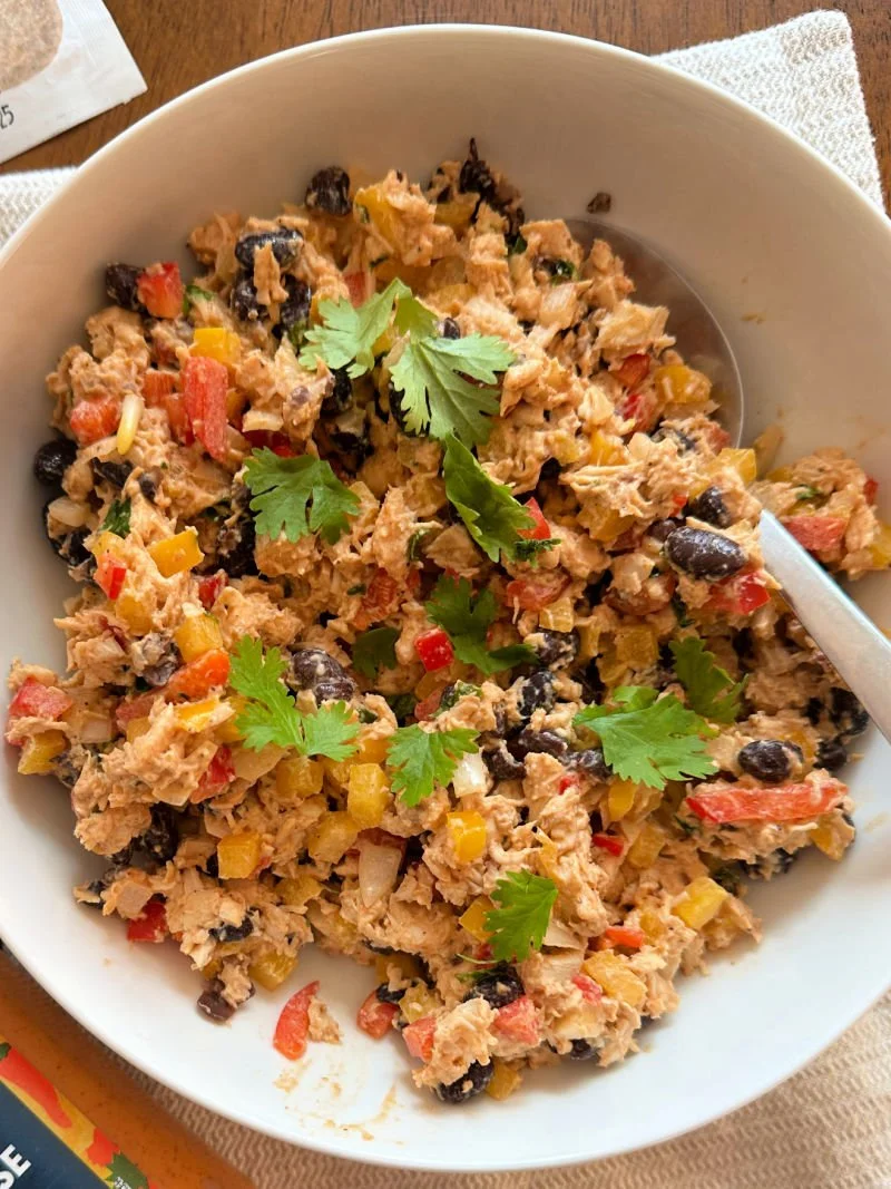 Southwest chipotle chicken salad in a bowl with red and yellow bell peppers, black beans, tomato, red onion, and cilantro