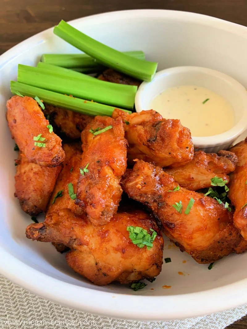 Crispy air fryer buffalo wings on a plate with high protein ranch dipping sauce and celery sticks