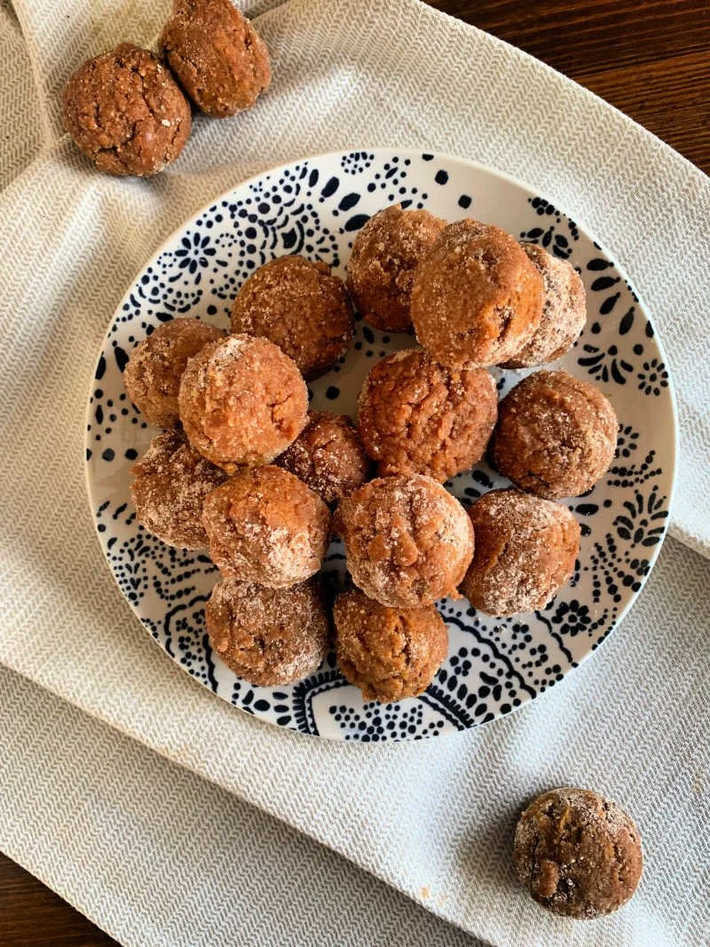 Low carb pumpkin spice mini muffins dusted with cinnamon monk fruit sugar in a pile, golden-brown and bite-sized