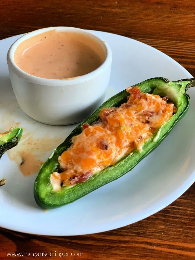 Easy jalapeño poppers with cream cheese cheddar filling and crispy bacon on a white serving plate