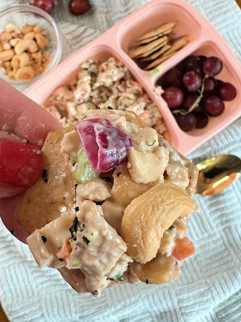 Honey mustard chicken salad with cashews, carrots, celery, and red onion in a glass bowl with avocado oil mayo dressing