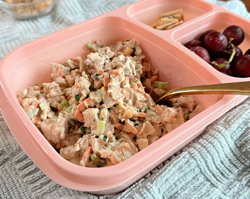 Honey mustard chicken salad with cashews, carrots, celery, and red onion in a glass bowl with avocado oil mayo dressing