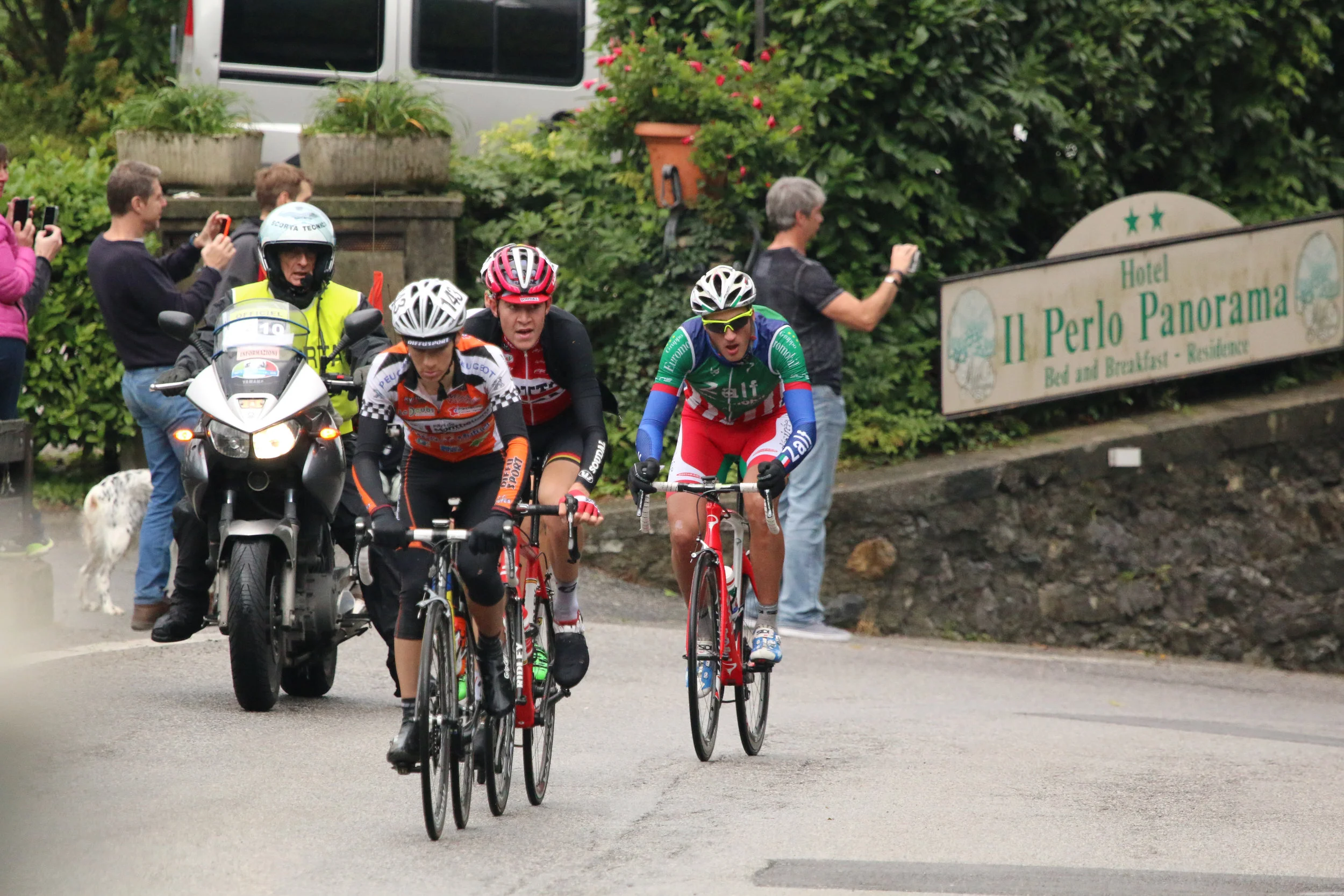 The U-23 Il Lombardia leaders at the steepest pitch of the Ghisallo climb in front of Hotel Il Perlo. Carlo and guests taking pics and videos. In the 2018 Il Lombardia race, Vincenzo Nibali almost rolled over Carlo’s shoes. This would be a very special vantage point for the Giro.