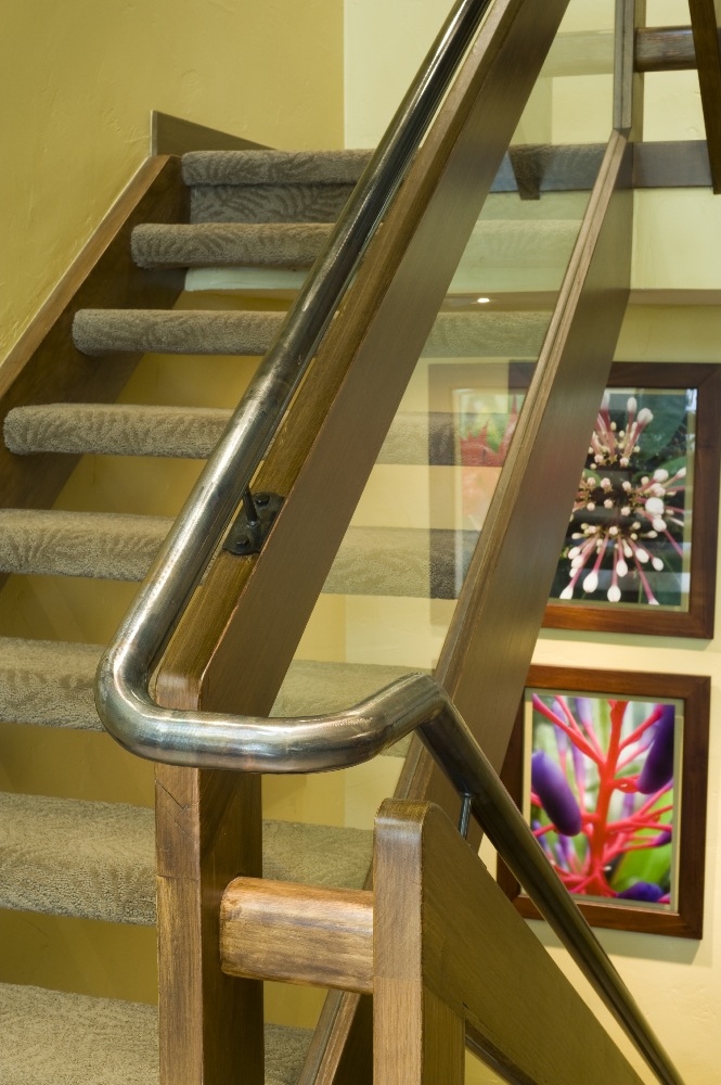 A 2x8 oak rail from the 80's was brought up to code by adding a floating 1 1/2" round steel pipe rail on top, that is continuous from basement to second floor.