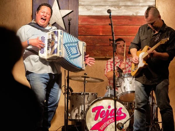 DMi is proud to sponsor TEJAS BROTHERS 7:00 pm August 12, 2017 When rock 'n' roll meets Tex-Mex in a honky tonk that is home to the blues, you get the Tejas Brothers . This quartet absolutely disregards any notions of staying within a certain “genre.” If it feels good, and makes people happy, it ought to be a Tejas Brothers song. Shows are family-friendly and focus on the idea that we only live once, and we should all get the most out of life. In 2013, the Dallas Observer Music Awards named the Tejas Brothers “Best Country Act.” Their latest CD, “Live a Little More,” was produced by Lloyd Maines. In 2009, they had the #7 album on the Americana Radio Airplay Charts. The Tejas Brothers is a four-piece band comprising accordion, upright bass, guitar, and drums. Shows can be acoustic or electric, and up to two hours in length. The Tejas Brothers’ repertoire of original and cover songs include: Boogie Woogie Mamacita (original); I Can’t Sleep (original); Don’t Be So Mean (original); Seven Spanish Angels; Hey Baby Que Paso; Crying Time; and El Sapito