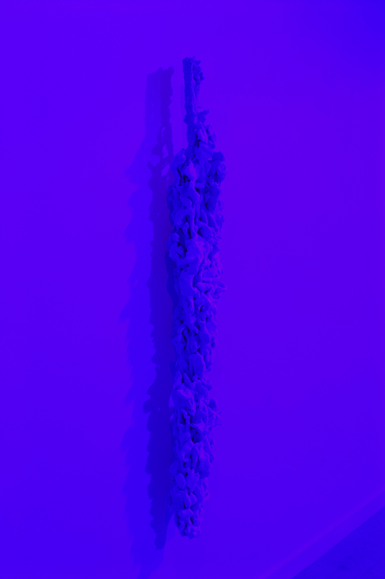   SOFIA LONDONO   Untitled , 2015, camo netting, hydrocal, silica sand, colbalt glass, 54" x 6" x 8" 
