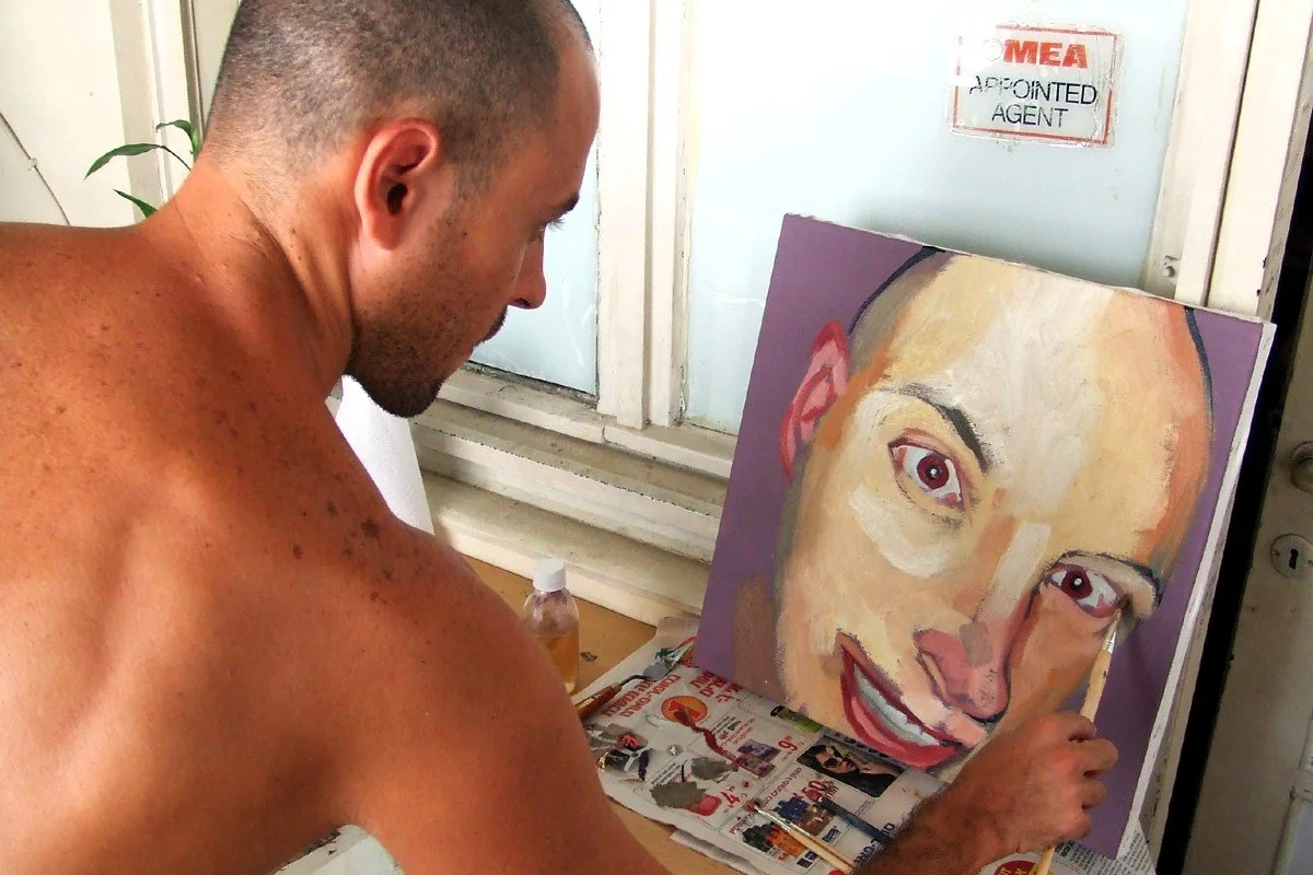 Artist Roi Pajursky during the creative process in his art studio, hand-painting an original portrait on canvas.