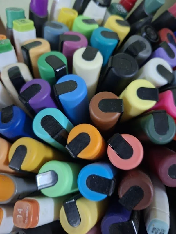 A variety of colorful acrylic paint markers arranged in an artist's workspace.