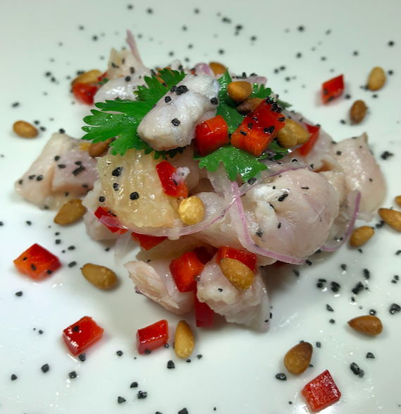 CEVICHE - Small tropical fin fish (usually snapper) diced and cured in lime juice, Mixed with grapefruit sections, red onion, cilantro and red bell pepper. Topped with paprika toasted pine nuts and black Hawaiian sea salt