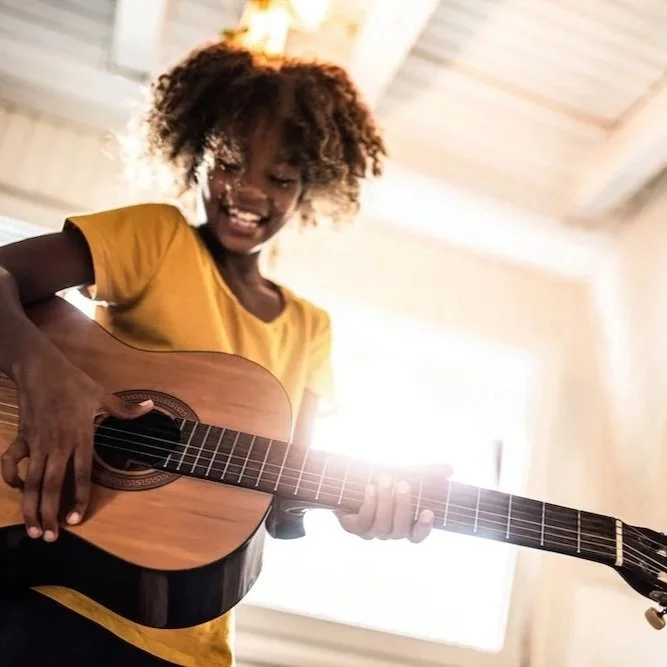 Student playing acoustic guitar during a music lesson at Collingswood Music