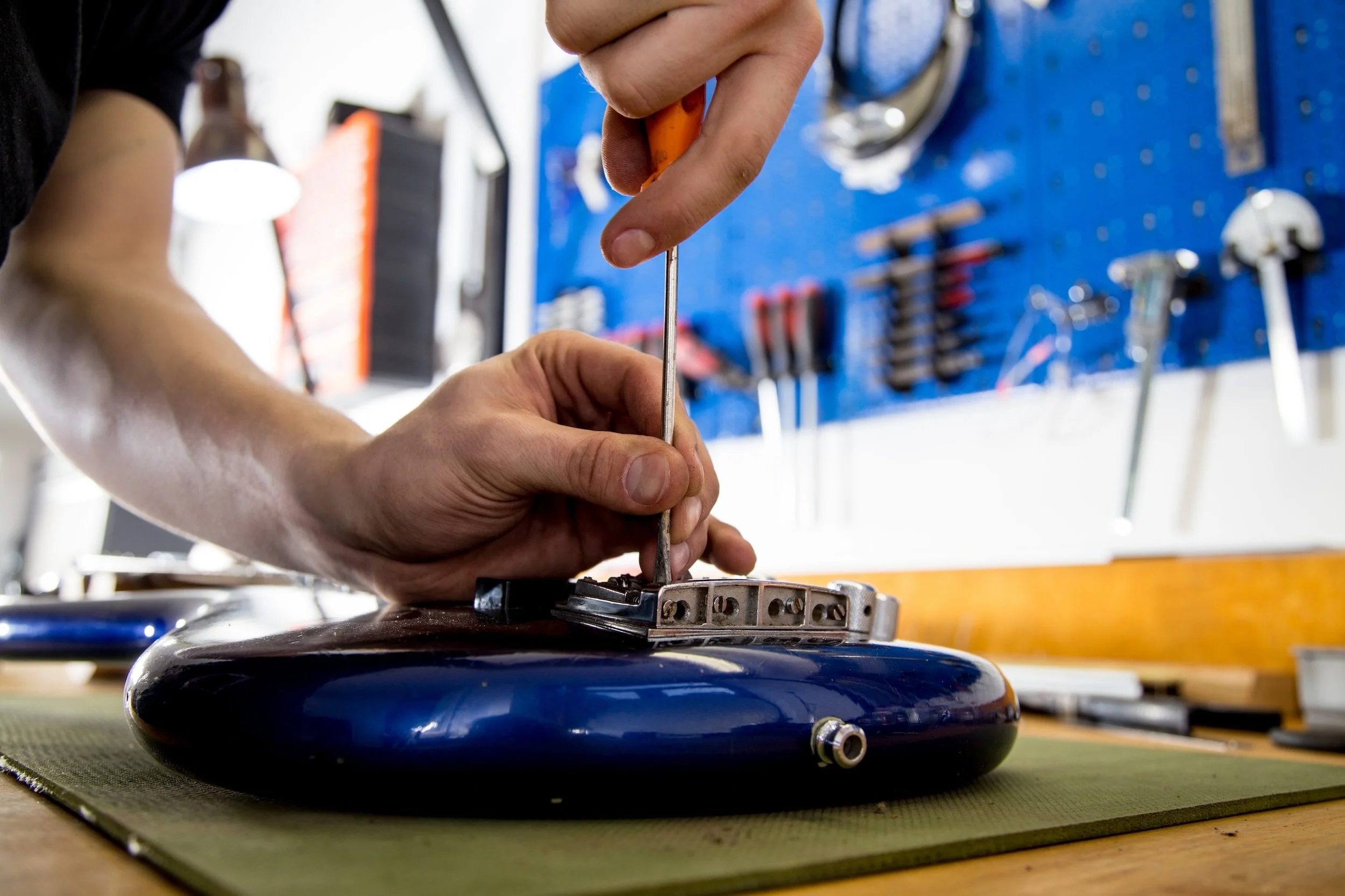 Repair technician tuning a guitar during a setup at Collingswood Music